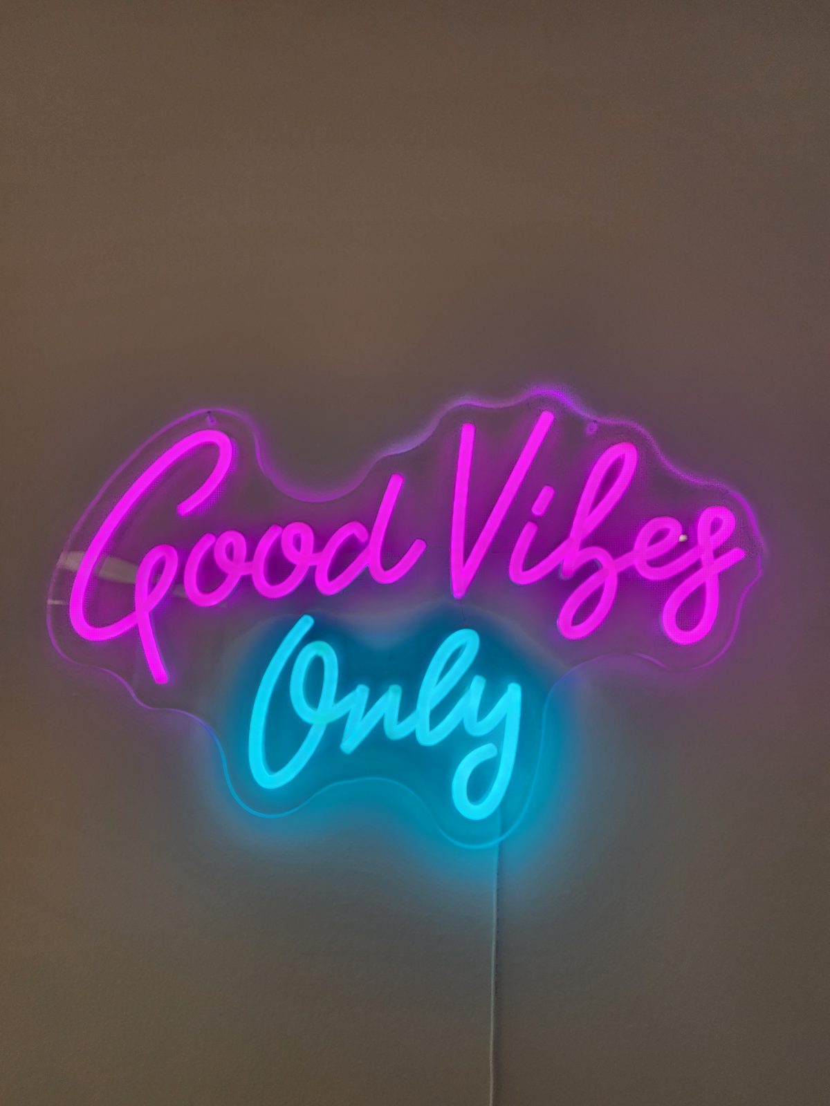 A neon sign reading Good Vibes Only, which hangs in both offices