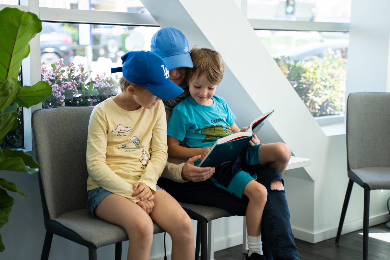 A parent reading to two children in the waiting room